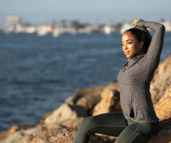 Silhouette of a woman stretching during sunrise with a bright background.